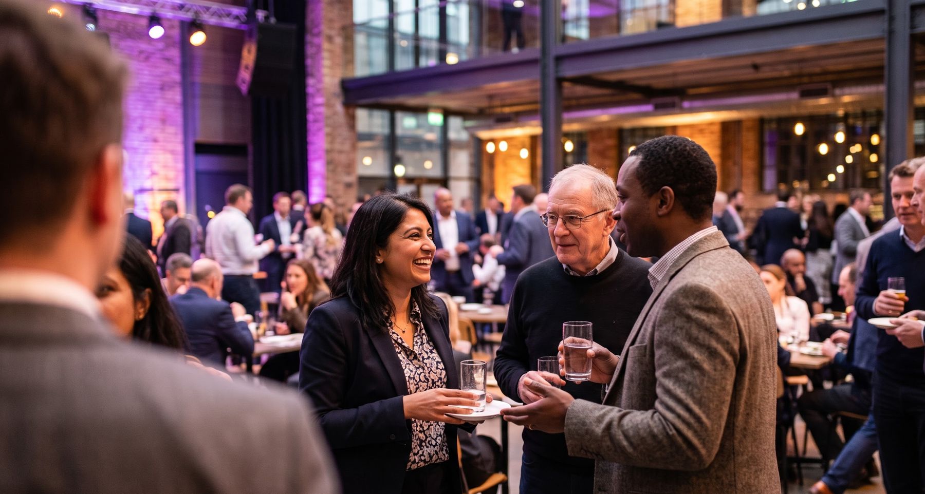 Guests networking and chatting at a corporate evening event in a converted warehouse venue